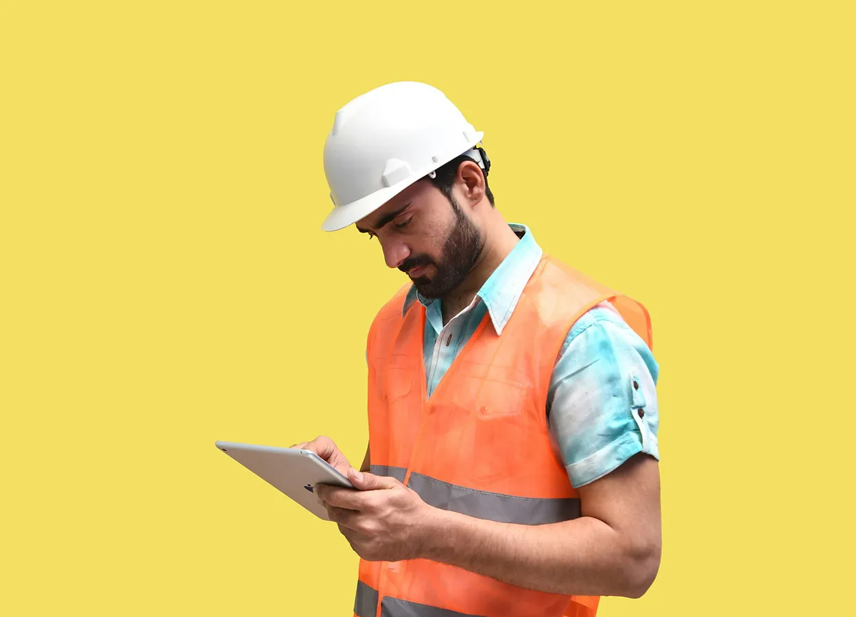 Baretli ve reflektörlü yelekli saha görevlisi tablete kayıt giriyor