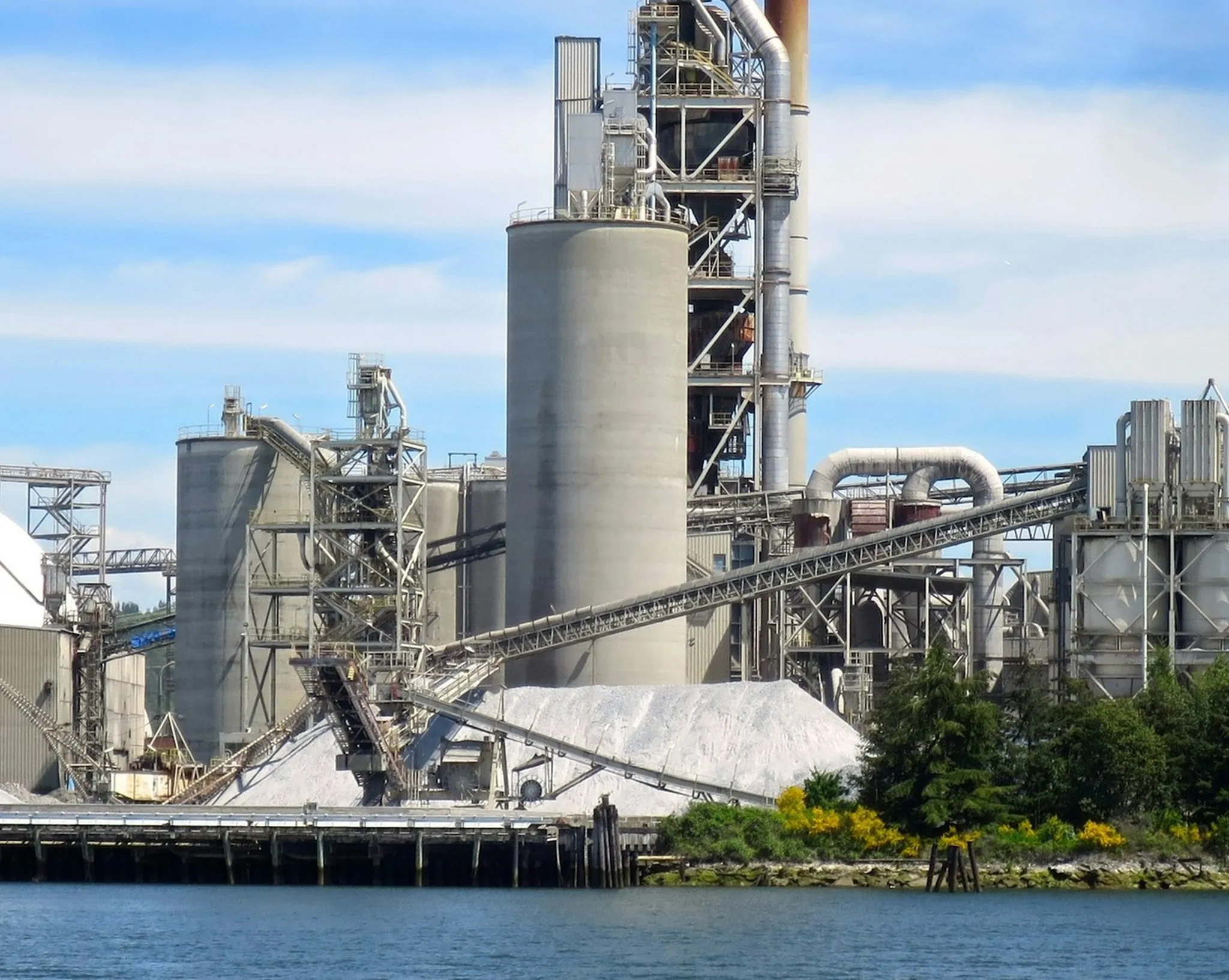 Deniz kıyısındaki çimento fabrikası, silolar ve klinker stok sahası