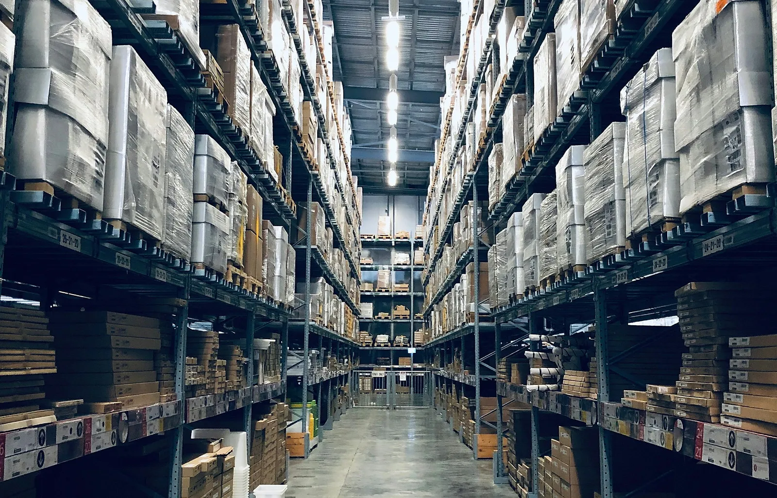 Raflarında paletli malzeme bulunan depo koridoru